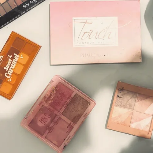 Paletas de sombra, blush e iluminador abertas sobre a mesa
